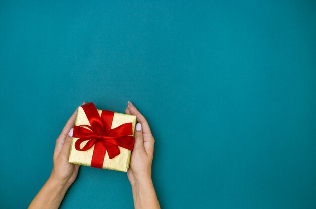 Female hands holding gift on blue background