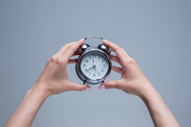 Free photo the female hands holding old style alarm clock