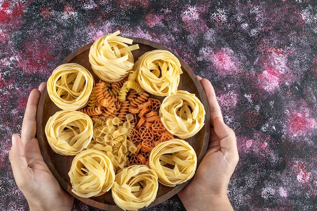 Female hands holding plate of various macaroni.