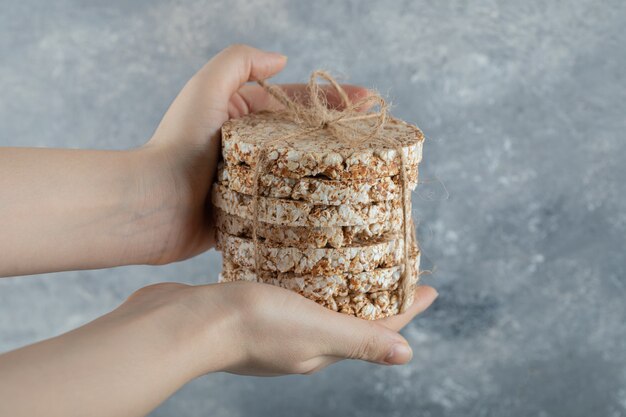 Female hands holding stack of rice cakes on marble surface