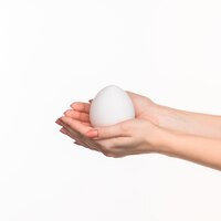 The female hands holding a white egg on white.