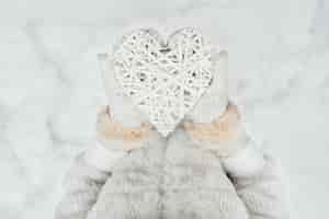 Бесплатное фото Женские руки в белых трикотажных рукавицах с переплетенным старинные романтические белые сердца