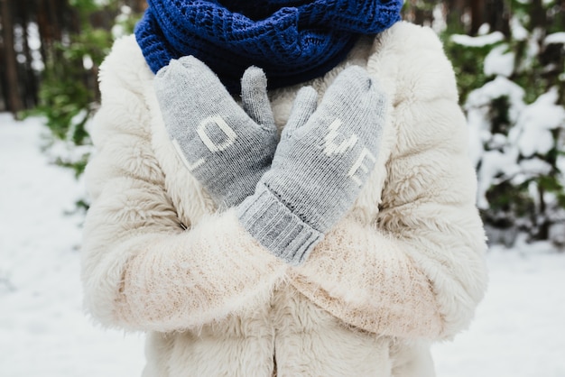 Free photo female hands in knitted mittens. on mittens embroidered with the word love.