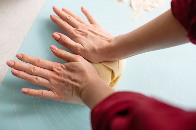 Female hands make dough at blue mat