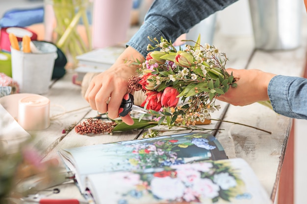 別の花の花束を作る女性の手