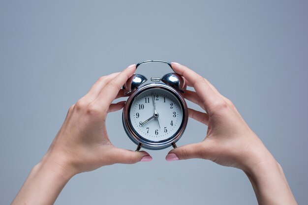 female hands and old style alarm clock