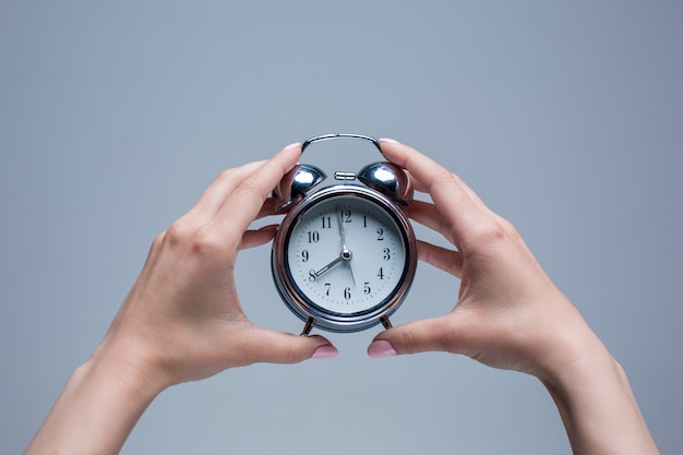 female hands and old style alarm clock