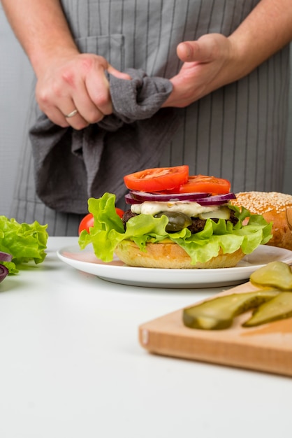 Mani femminili che preparano un gustoso hamburger