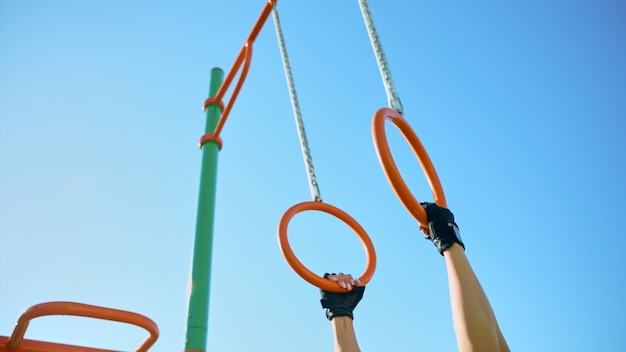 Mani femminili che prendono anelli di ginnastica al campo sportivo