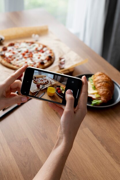 Female hands taking photo of a sliced pizza and a glass of orange juice