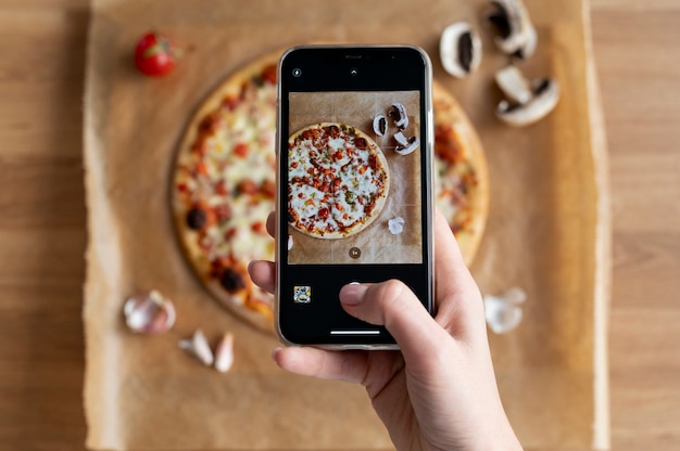 Foto gratuita mani femminili che scattano foto di pizza a fette