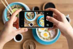 Free photo female hands taking photo of two bowls of ramen