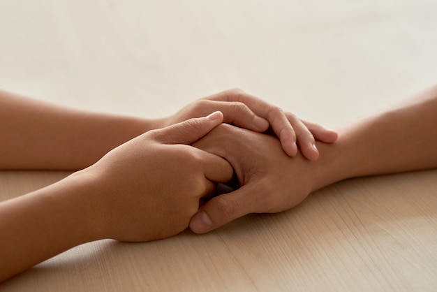 Female hands touching male hands reassuring boyfriend 