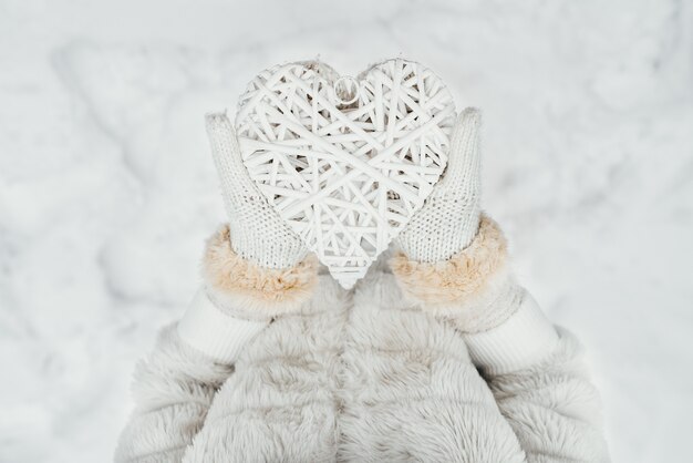 Женские руки в белых трикотажных рукавицах с переплетенным старинные романтические белые сердца