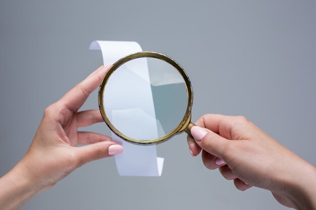 female hands with  empty transaction paper or check and magnifier