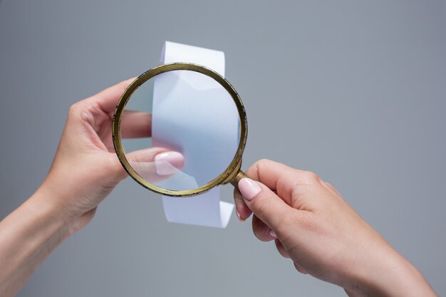 The female hands with  empty transaction paper or check and magnifier
