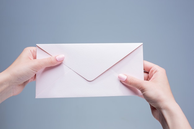 The female hands with the envelope against the gray background