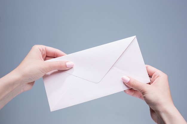 female hands with the envelope against the gray background