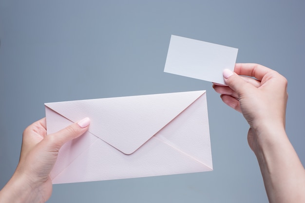 female hands with envelope against gray