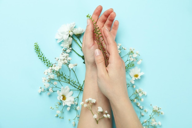 Female hands with flowers on blue background