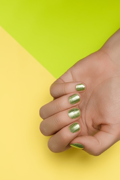 Female hands with green nail design. Green nail polish manicured hands. Female hands on green background