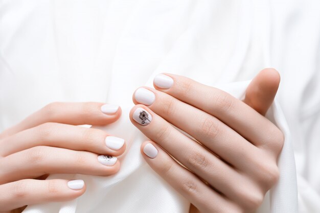 Female hands with white dandelion nail design.