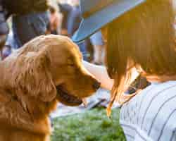 Foto gratuita femmina in un cappello che accarezza un adorabile simpatico cane marrone retriever