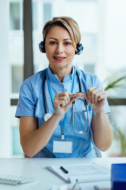 Female healthcare worker advising patients while working at hospital call center and looking at camera