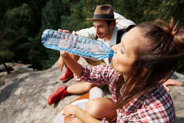 Женщина-путешественница пьет воду в горах