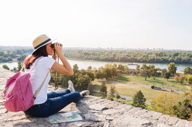 Female hiker looking at view through binoculars