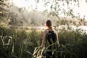 Foto gratuita viandante femminile che cammina nell'erba verde vicino al lago