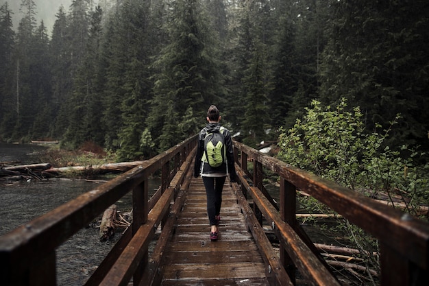 Foto gratuita viandante femminile che cammina sul ponte di legno