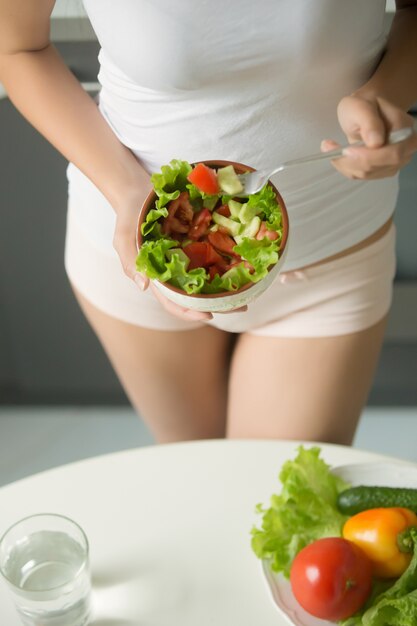 Female holding bowl of salad against her waist