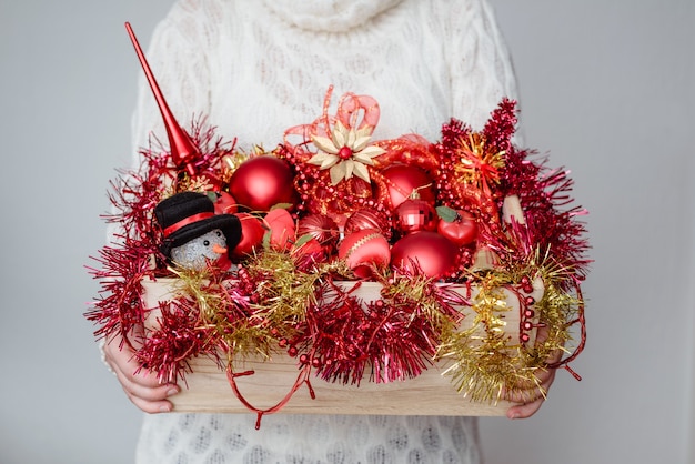 Female holding a box of red Christmas ornaments