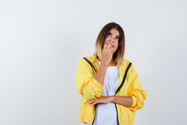 female holding hand on chin in t-shirt, jacket and looking dreamy , front view.