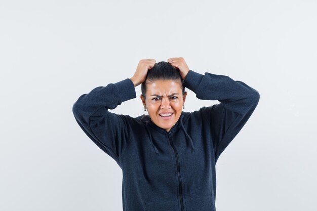 Free photo female holding hands on head in hoodie and looking nervous , front view.