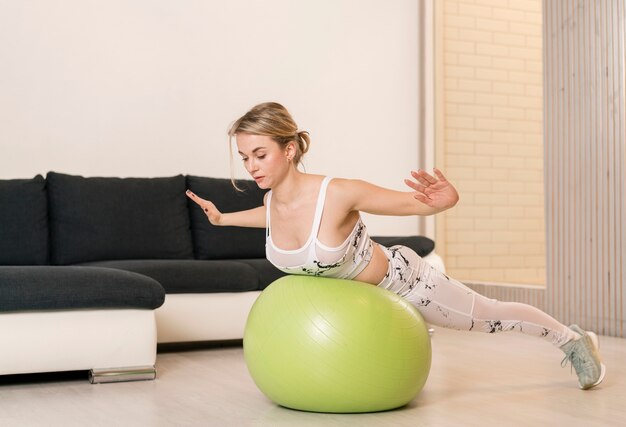 Foto gratuita femmina a casa lavorando su palla fitness