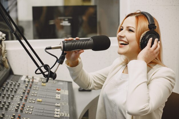 마이크에서 통신하는 여성 호스트. 라디오 스튜디오에서 여자입니다.