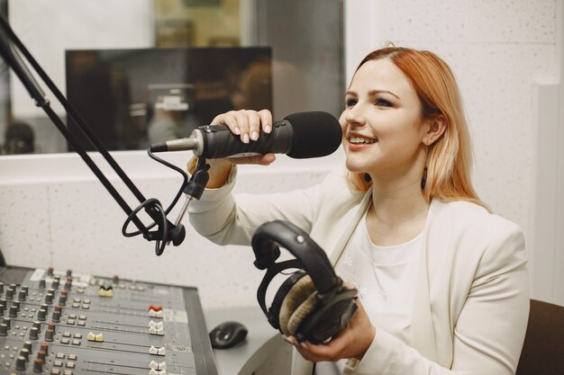 Хозяин женского пола общается по микрофону. Женщина в радиостудии.