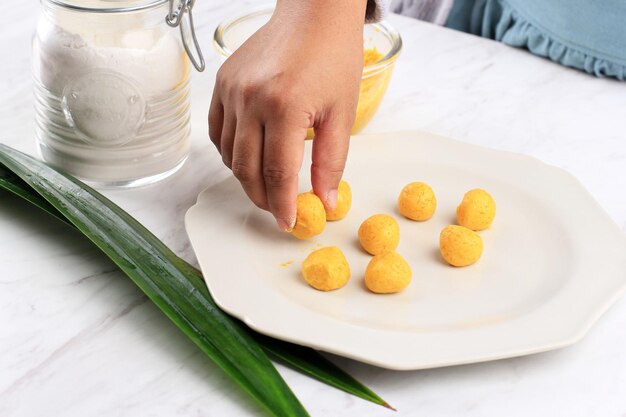 女性のインドネシア人パットビジサラクカボチャ、黄色いサツマイモまたはカボチャのライスケーキ、ブカプアサラマダンの朝食用のタクジルを作るキッチンでの調理プロセス