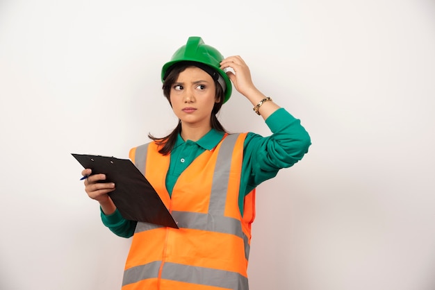 Female industrial engineer in uniform with clipboard on white background.