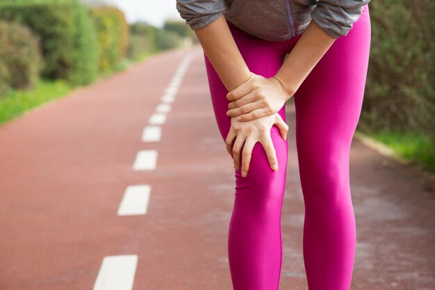 Female jogger wearing pink tights, injuring knee