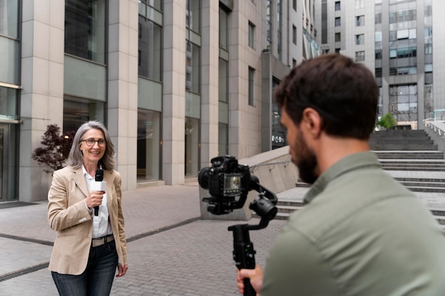 Female journalist taking an interview next to her cameraman
