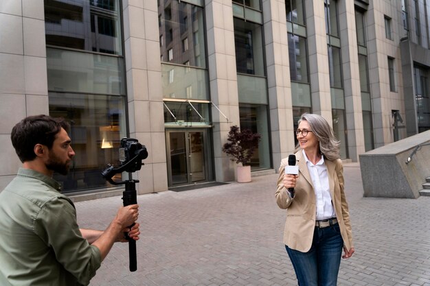 Foto gratuita giornalista che fa un'intervista accanto al suo cameraman