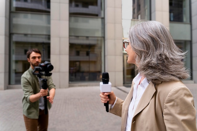 カメラマンの隣でインタビューをしている女性ジャーナリスト