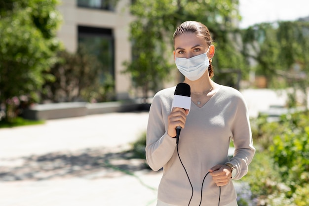 医療マスクを持つ女性ジャーナリスト