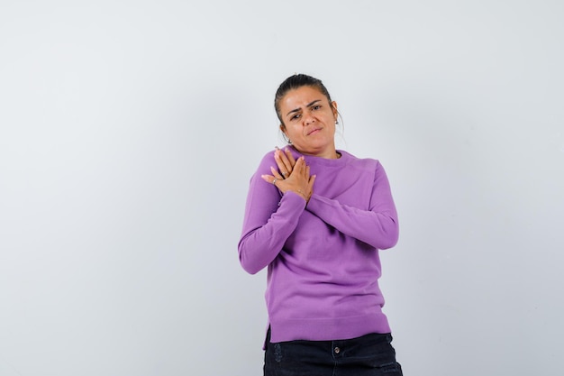 Female keeping hands on chest in wool blouse and looking gloomy 