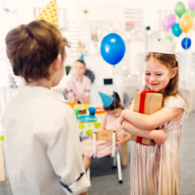 Free photo female kid holding present with red ribbon