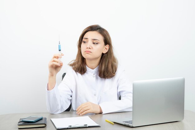 Female laboratory researcher holding syringe with blue liquid . High quality photo