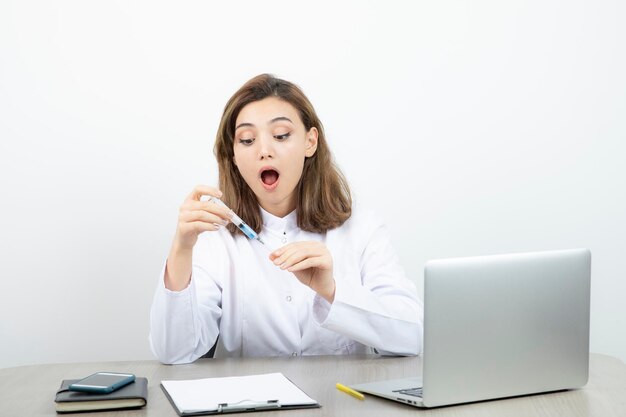 Female laboratory researcher holding syringe with blue liquid . High quality photo